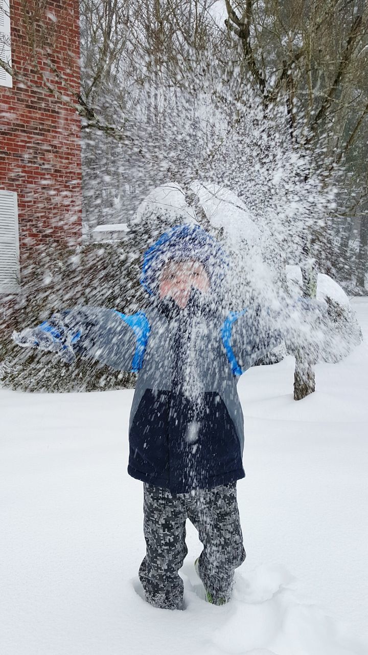 Kid throwing snow in back yard