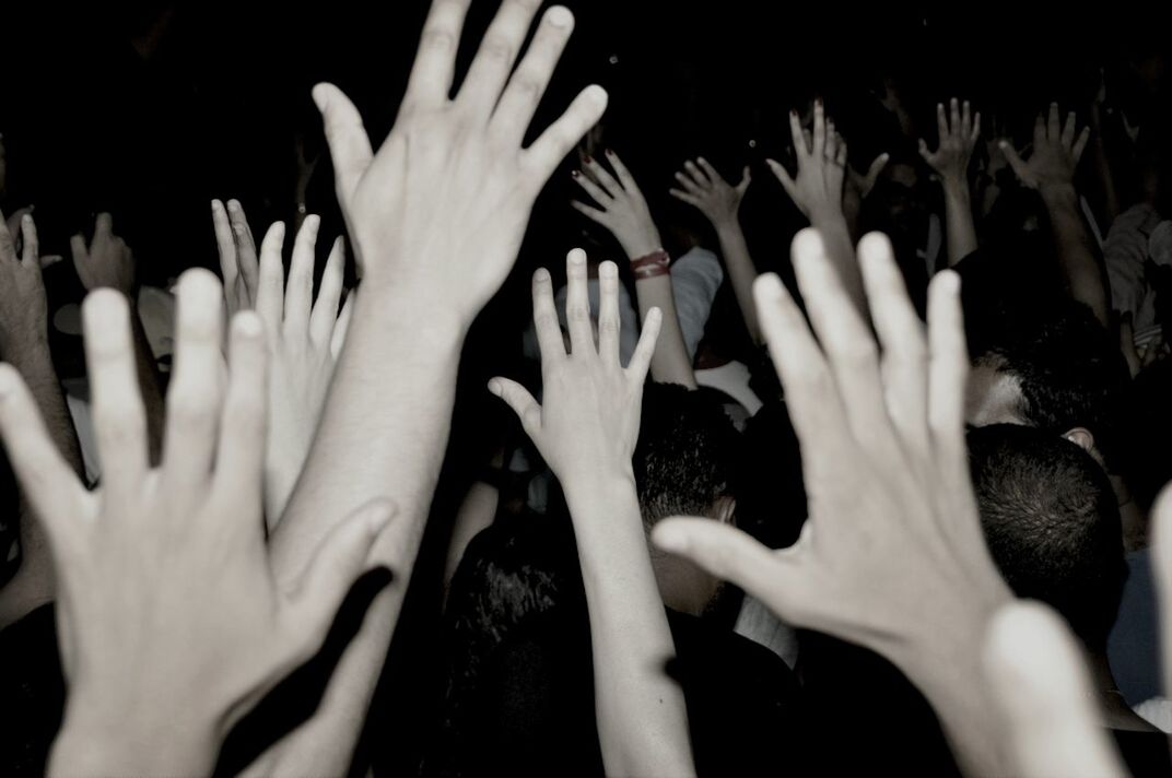 Close-up of raising hands over black background