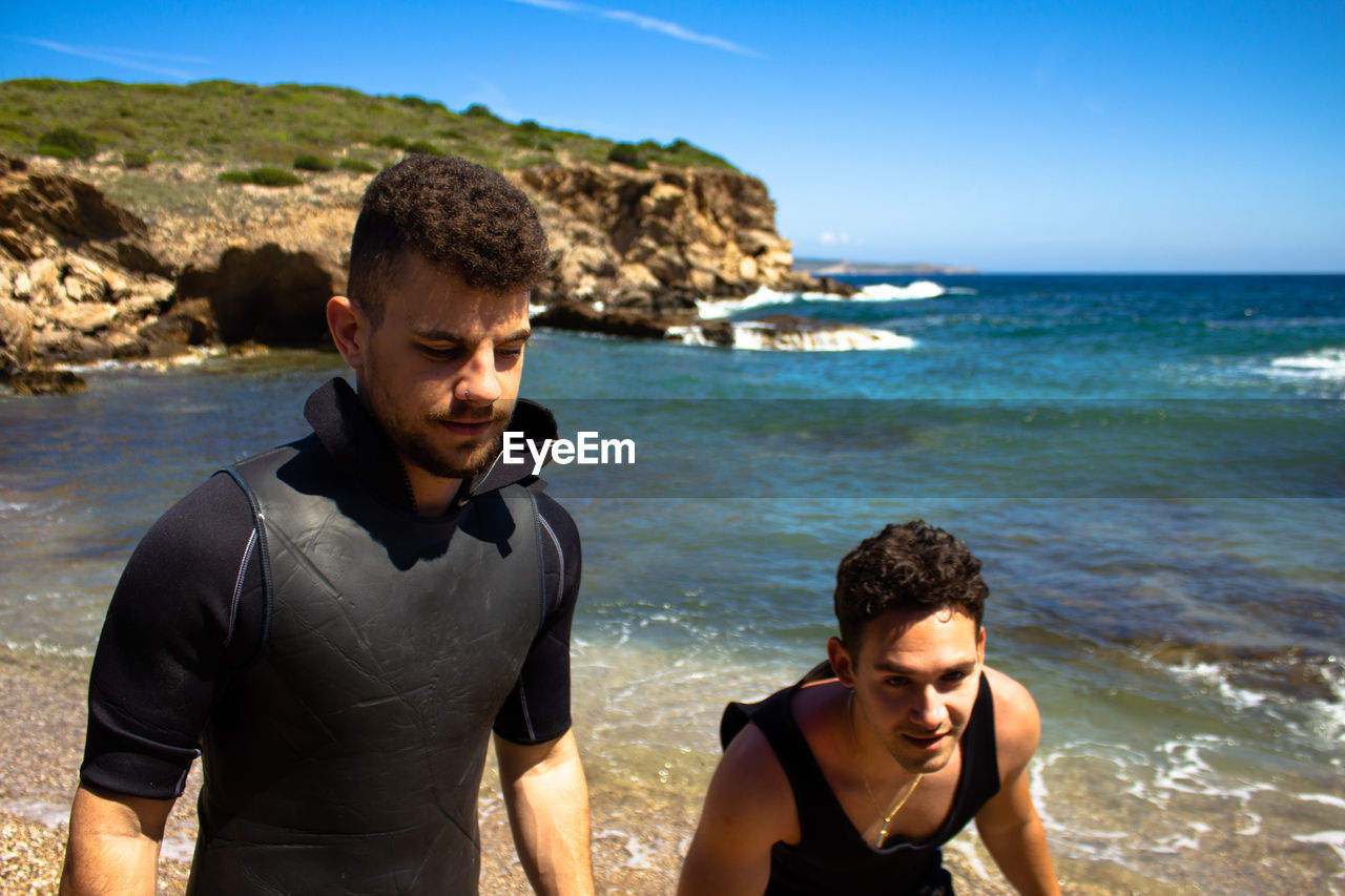 Male friends at beach against clear sky