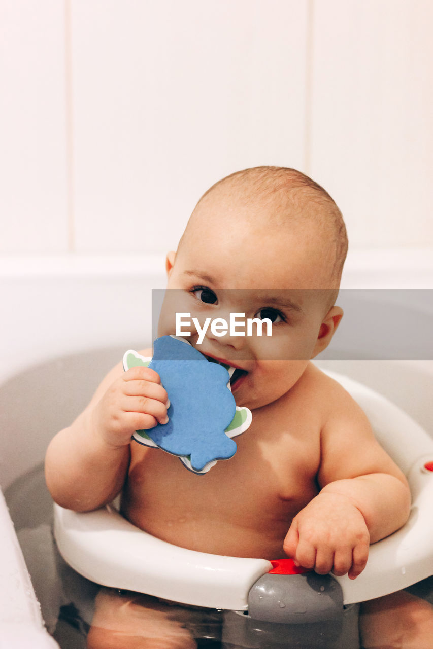 Sweet funny baby taking a bath. baby chewing a toy in a bath chair.