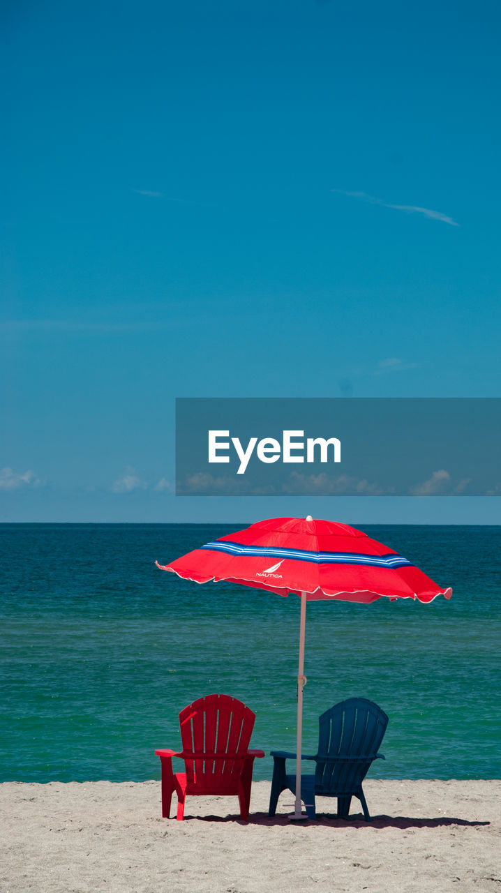 RED CHAIRS ON BEACH AGAINST SKY