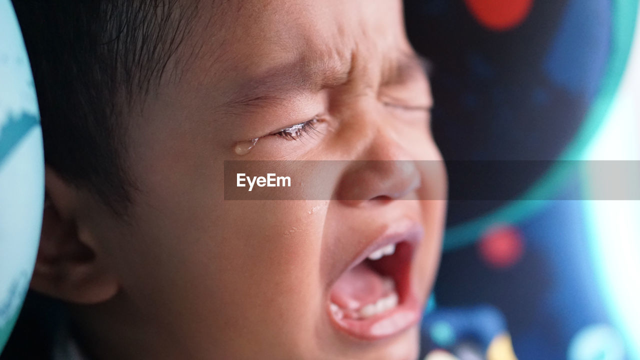 Close-up of baby boy crying in car