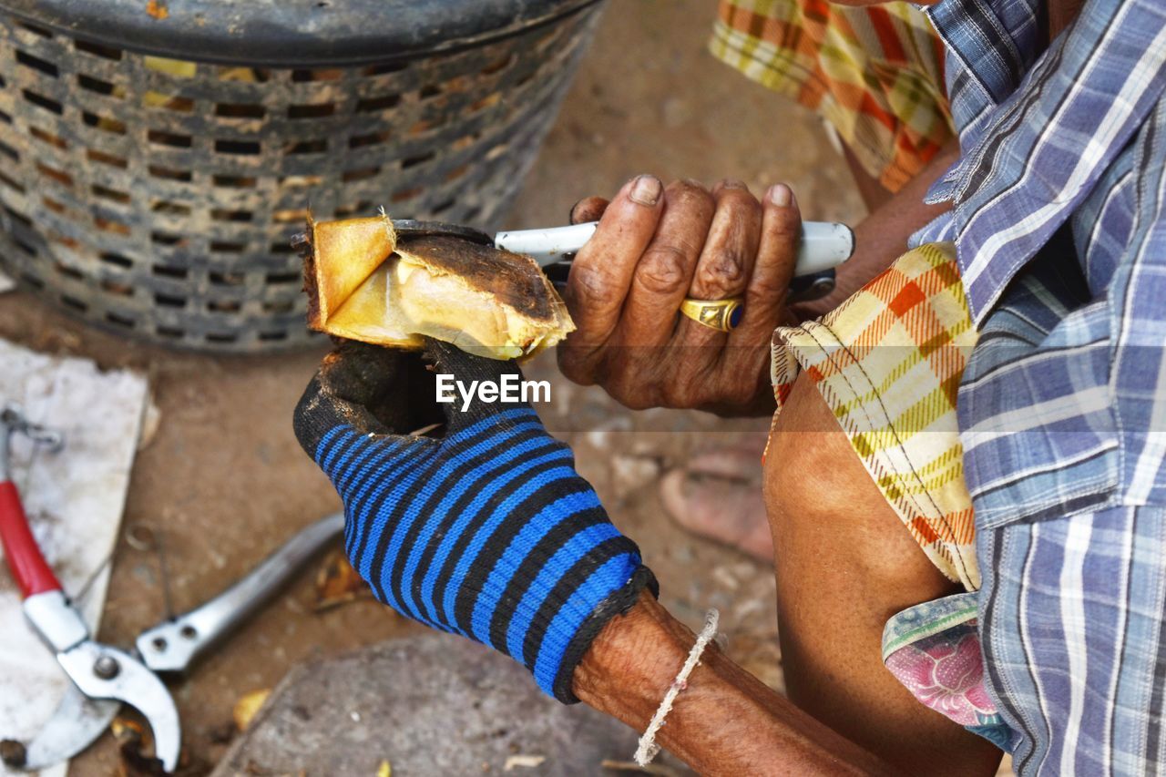 Midsection of man cutting mango seed