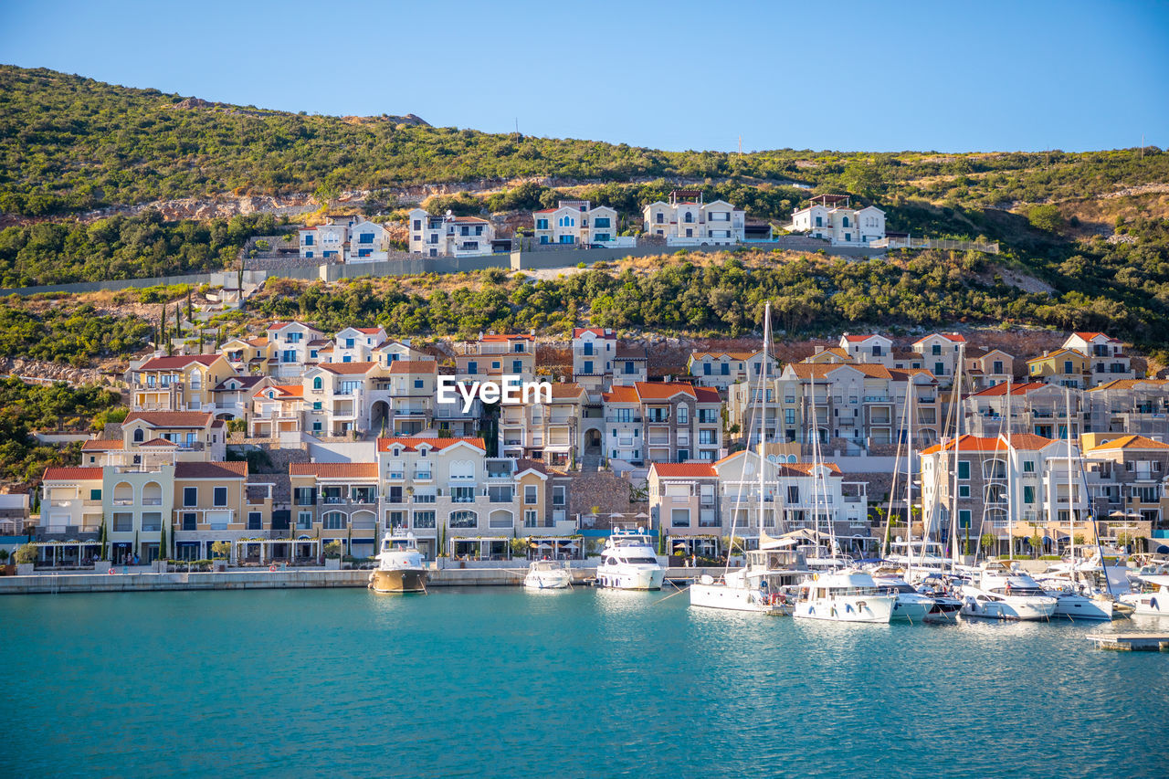 SAILBOATS IN SEA AGAINST HOUSES IN TOWN