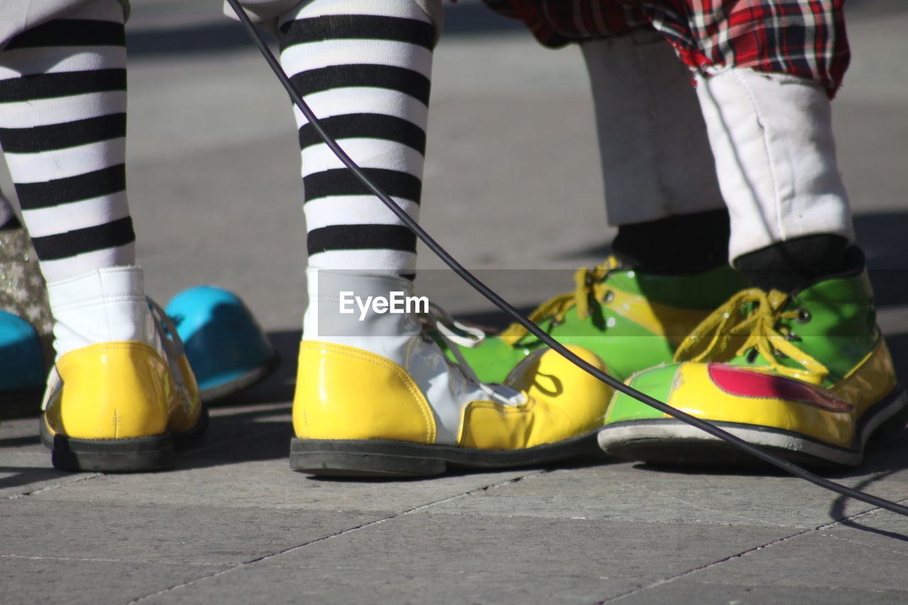 Low section of people wearing clown shoes while standing on street