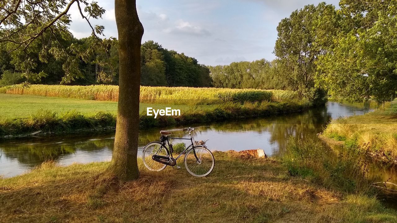 Bicycle on field by lake against sky