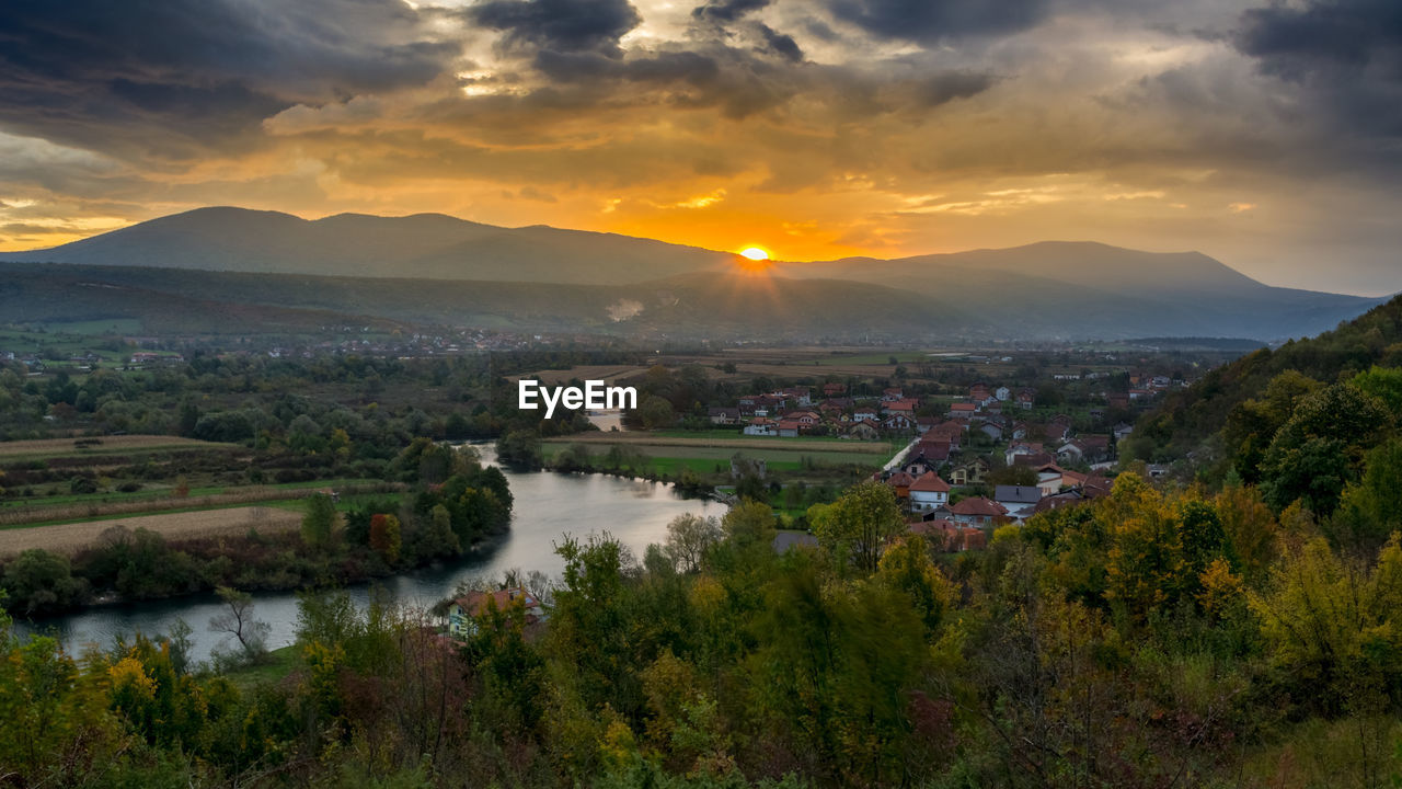 HIGH ANGLE VIEW OF RIVER AND TOWNSCAPE AGAINST SKY