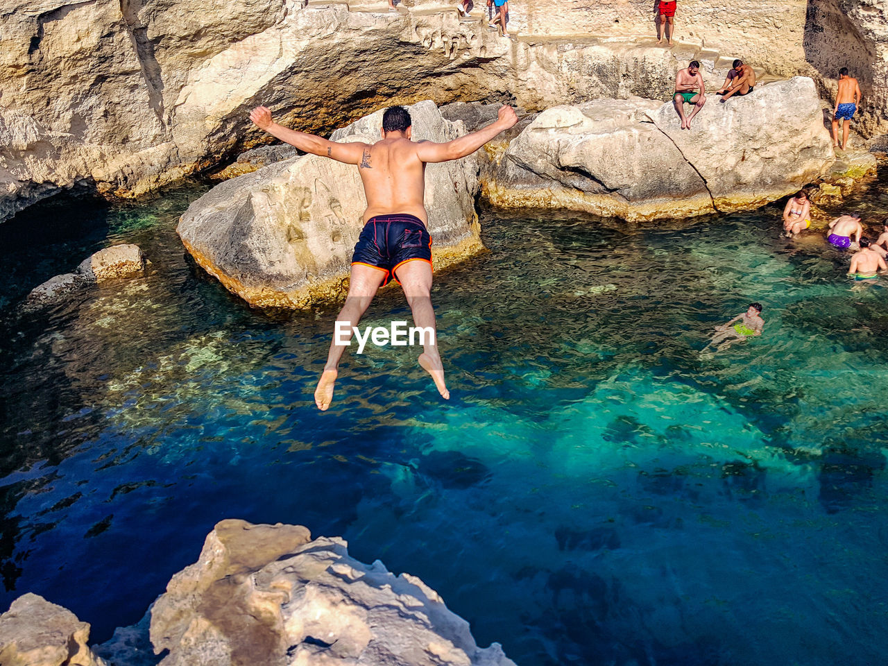 Rear view of shirtless man jumping in lake