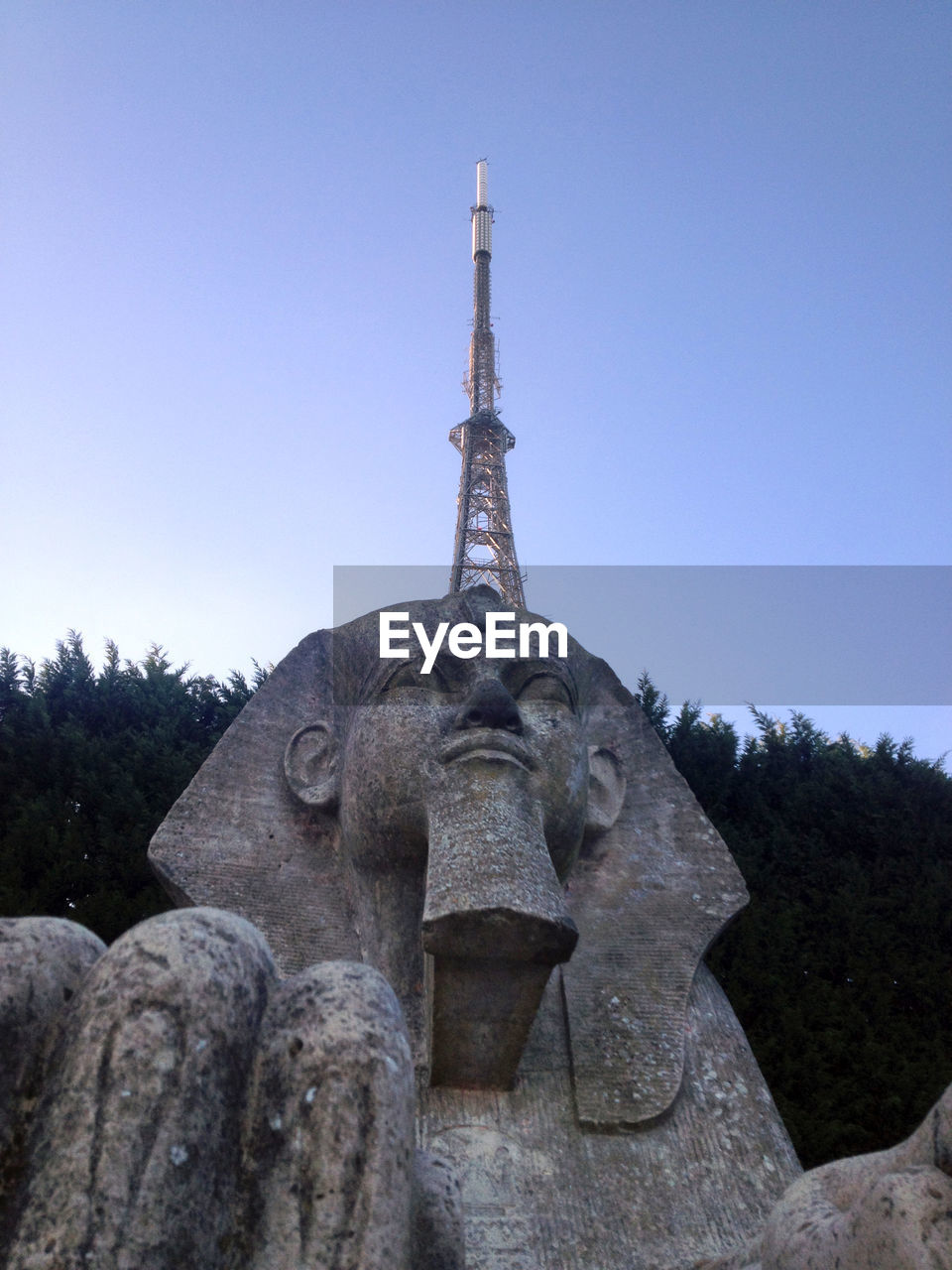 Low angle view of the sphinx statue by communication tower against clear sky