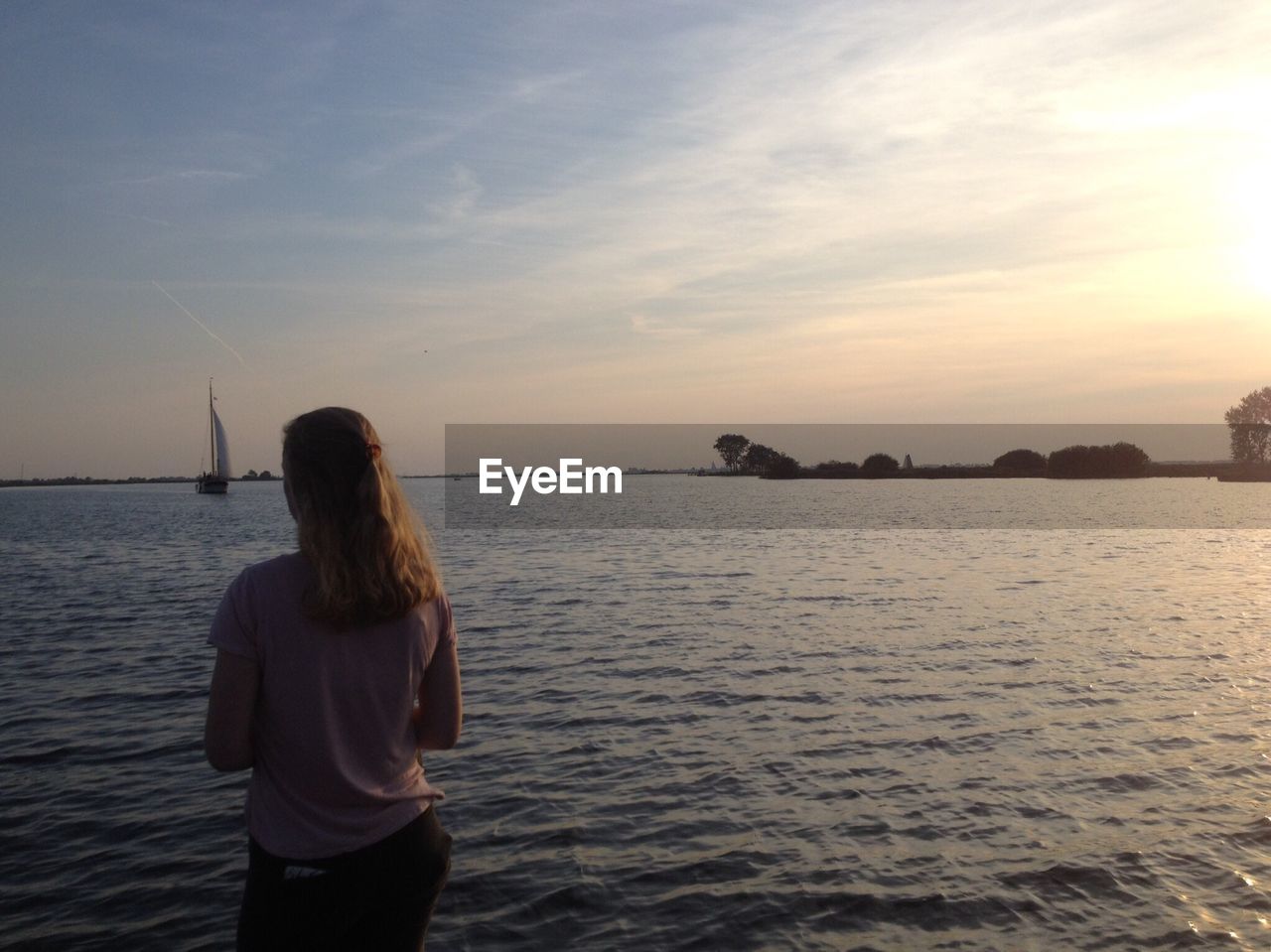 REAR VIEW OF WOMAN STANDING BY SEA AGAINST SKY