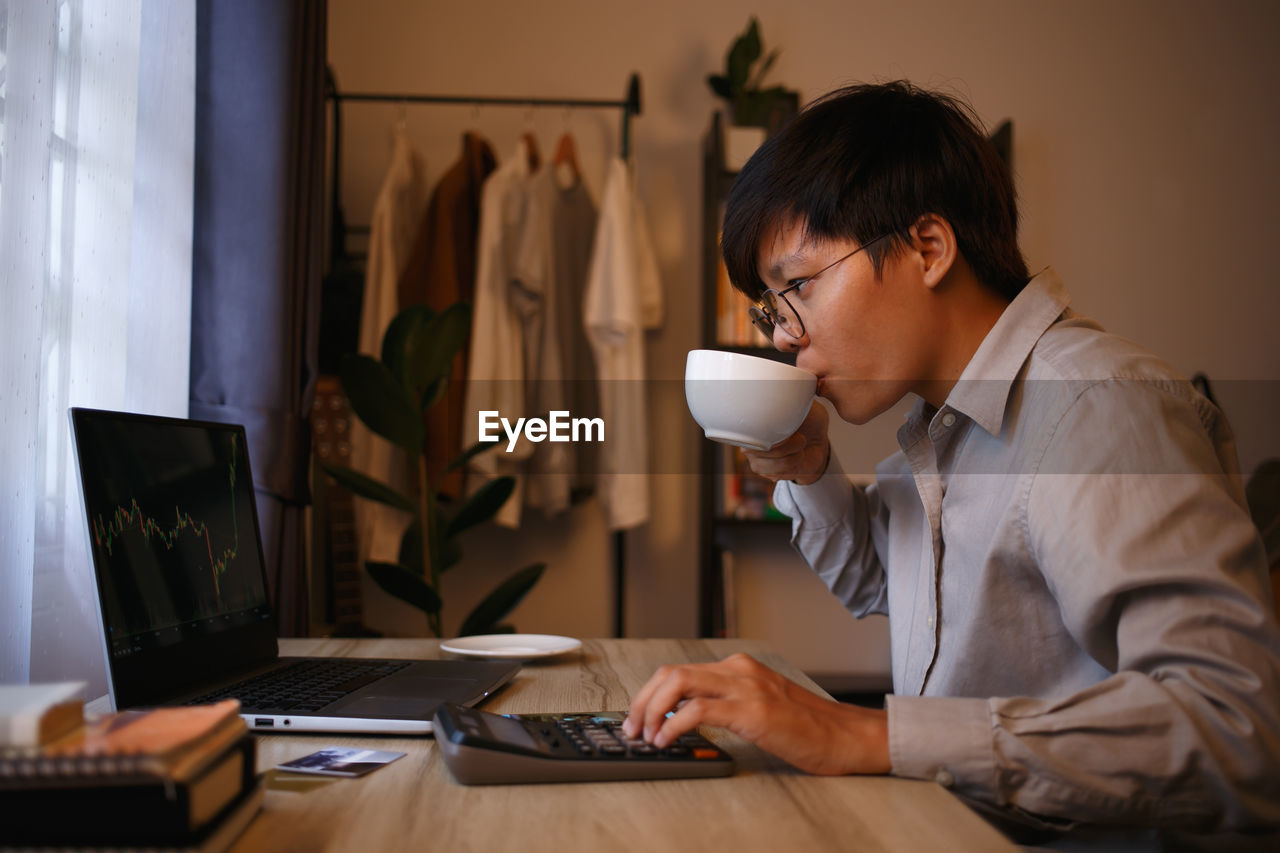 side view of man using laptop at table