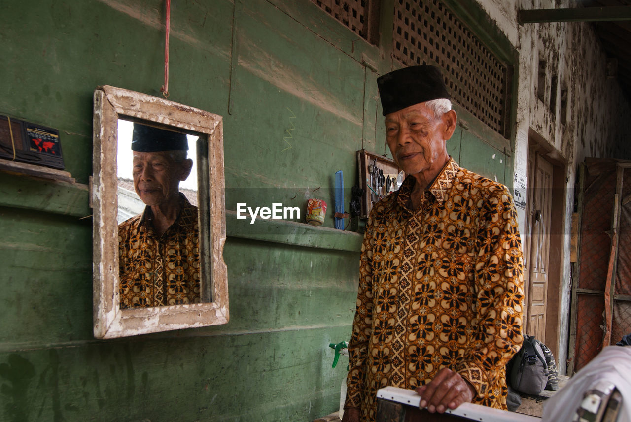 Man with reflection in mirror standing at home