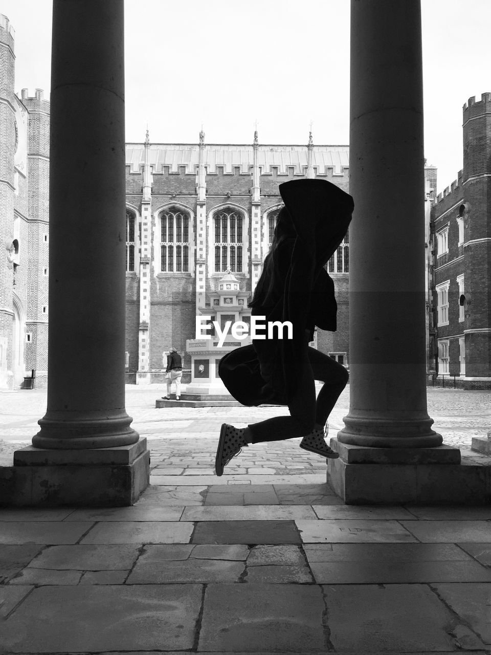 Side view of person jumping next to pillars