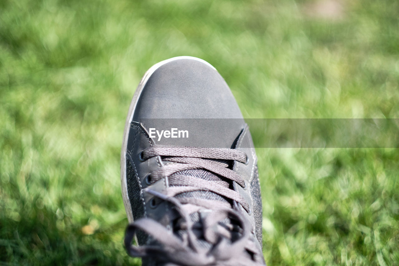 CLOSE-UP OF SHOES ON FIELD BY GRASS