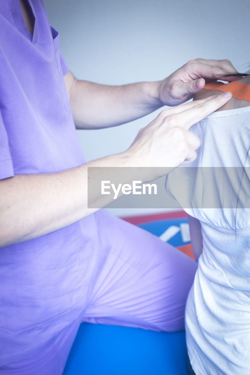 Midsection of doctor examining patient shoulder in hospital