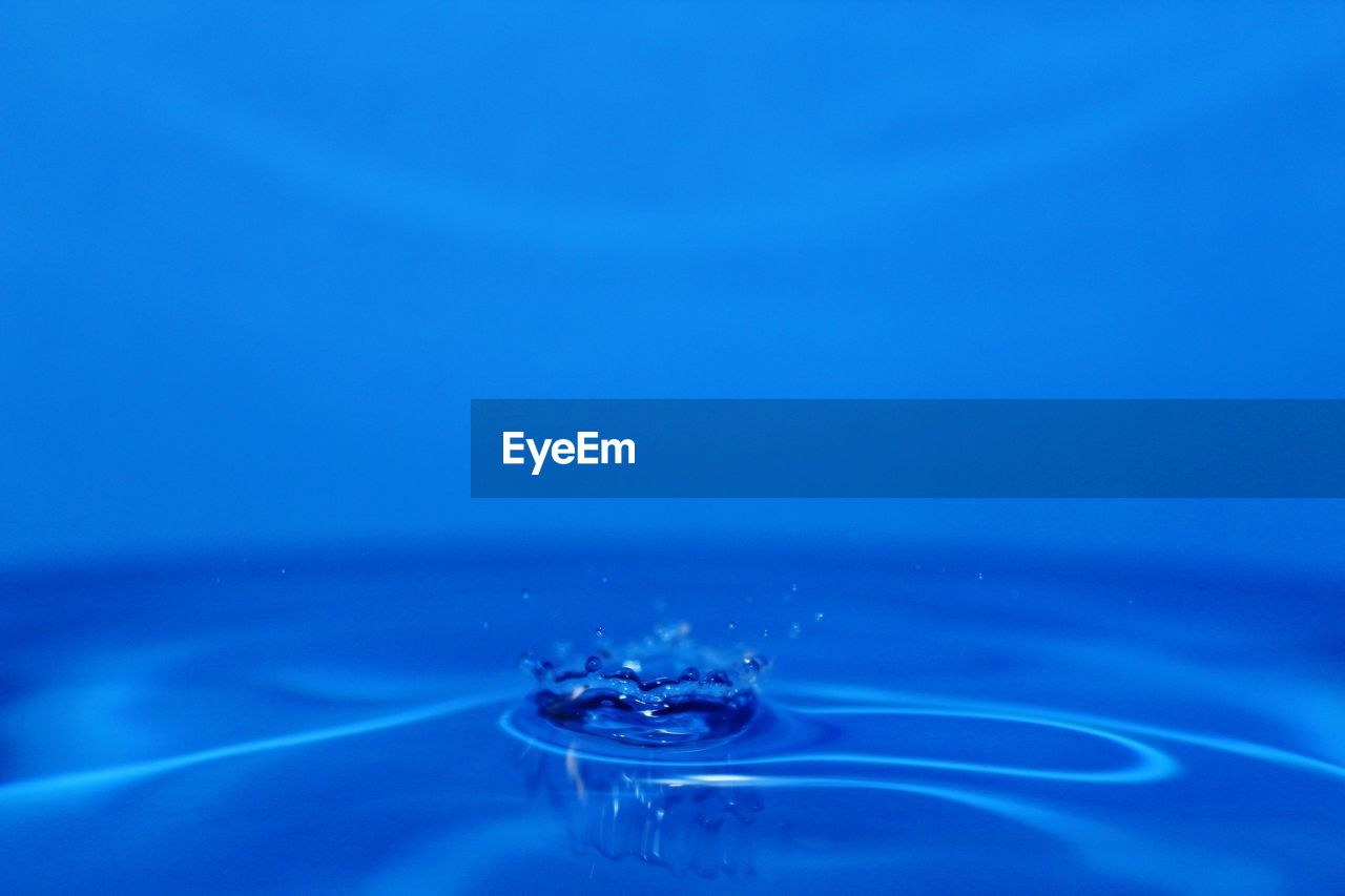 Close-up of drop falling on blue water