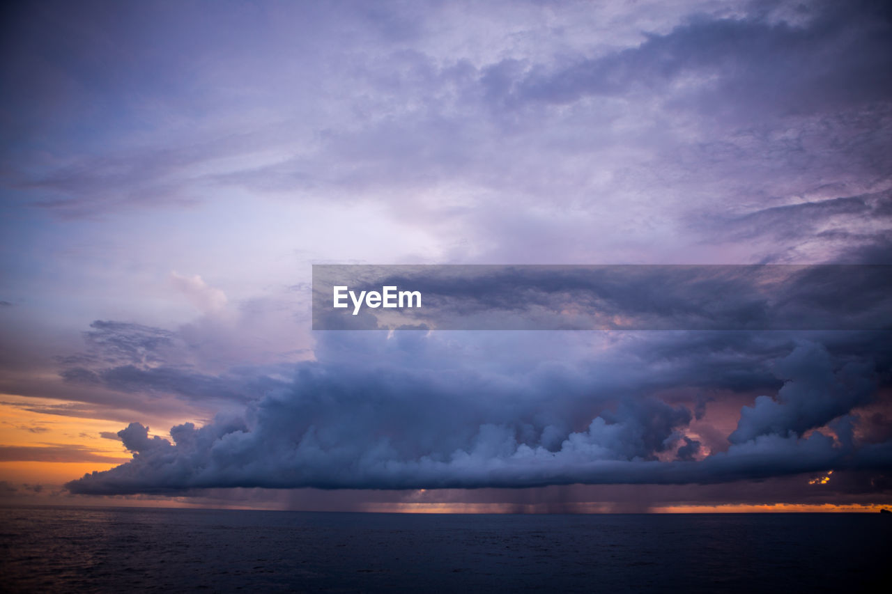 Scenic view of sea against cloudy sky at dusk
