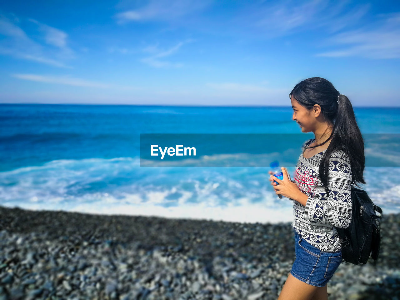 Young woman on beach against sky