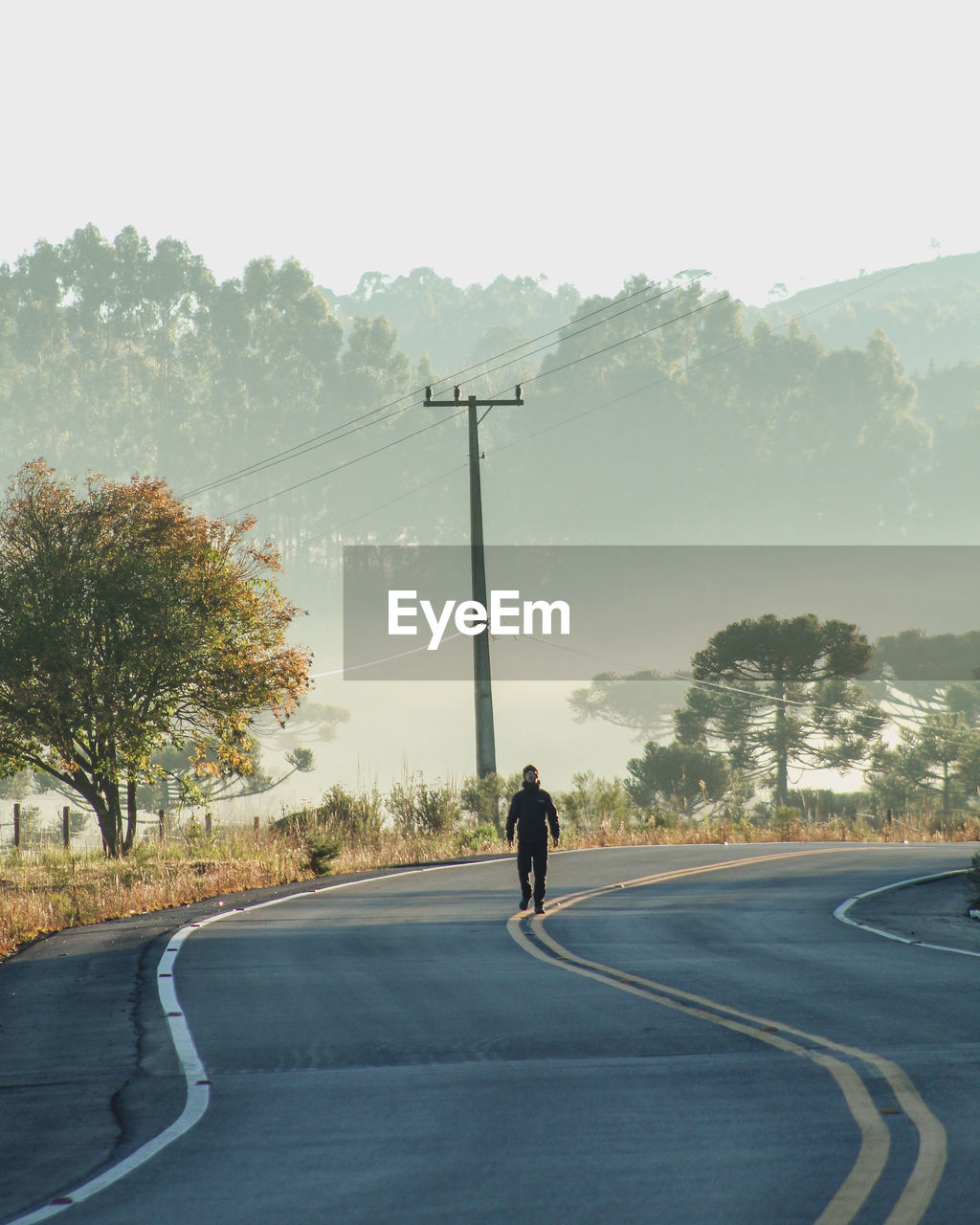 Rear view of man walking on road against sky