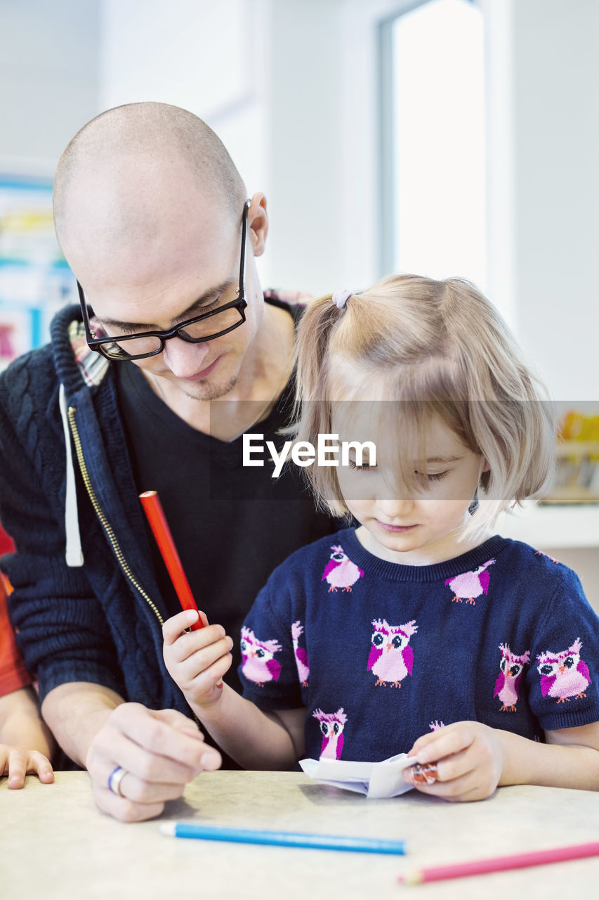 Teacher wit girl in art class at kindergarten