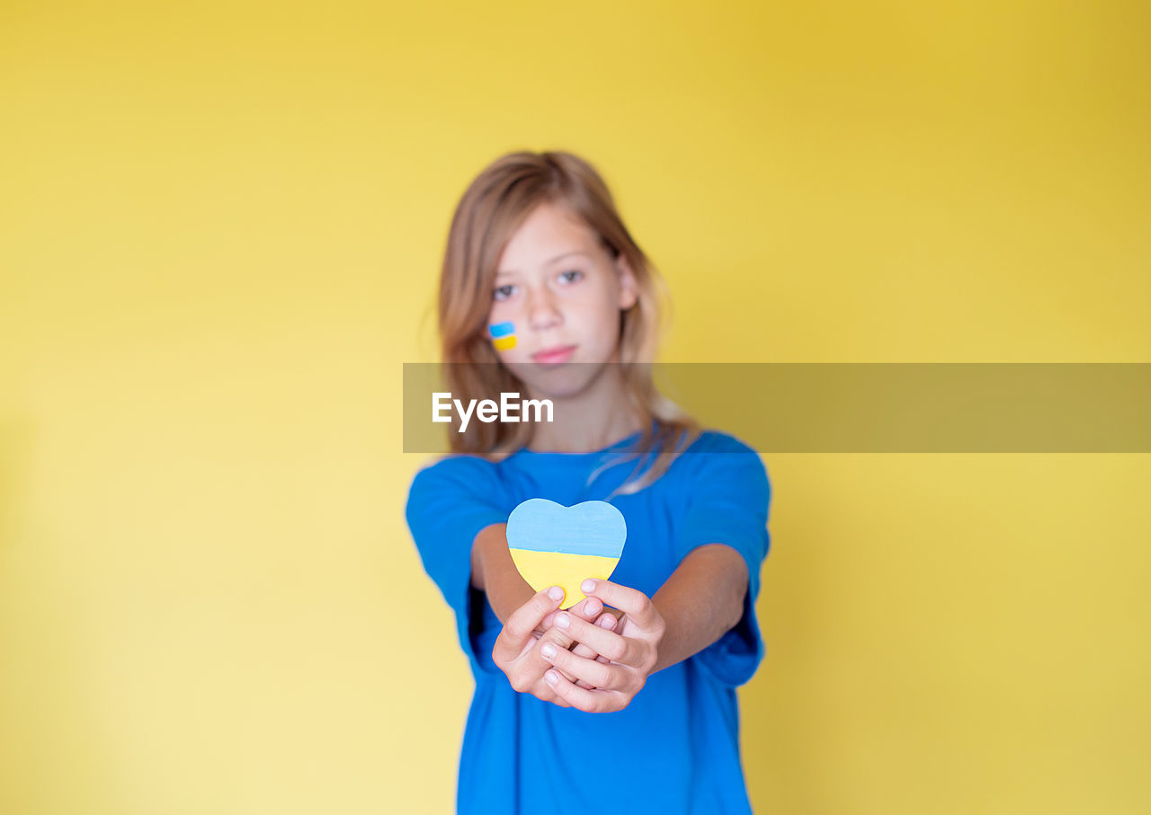 Portrait of smiling girl standing against yellow background