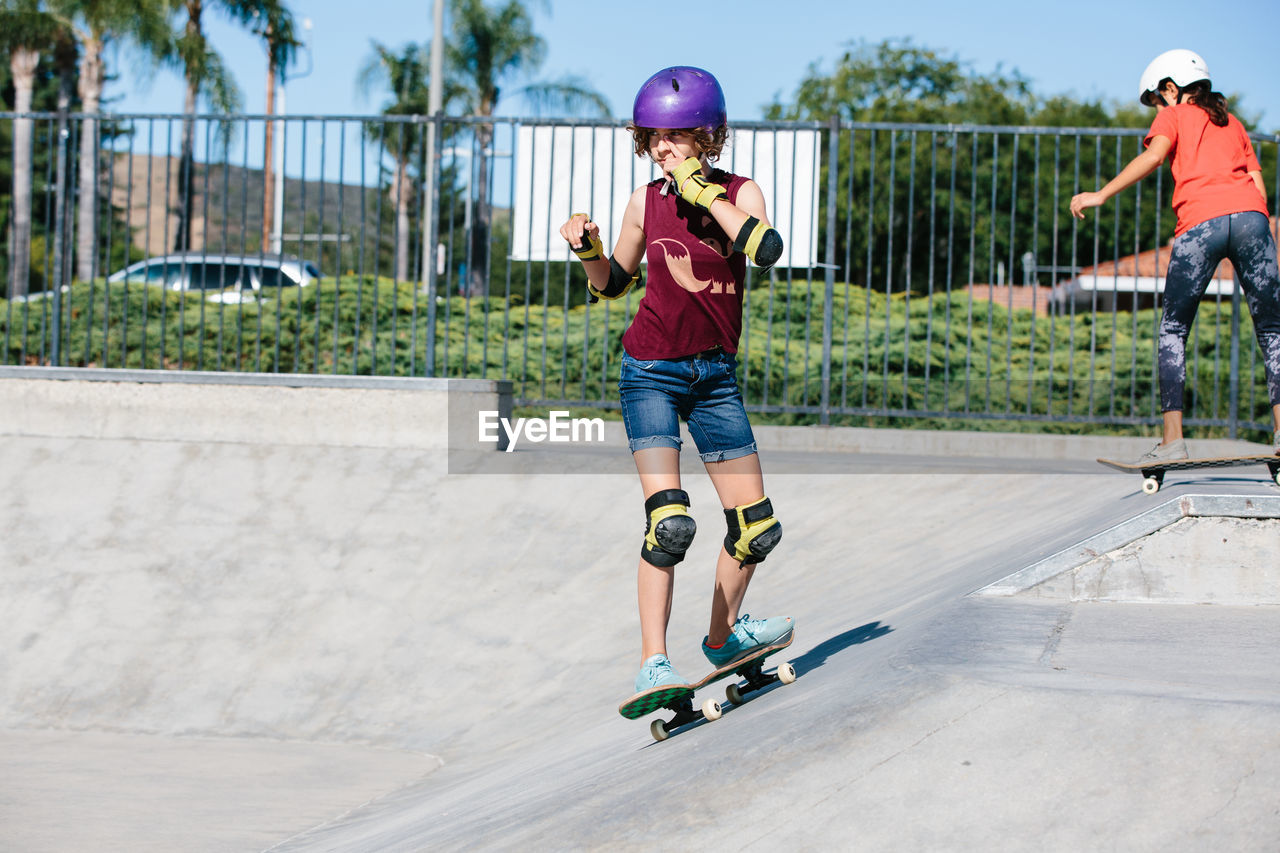 Teen girl skateboards at a skatepark while scratching her face