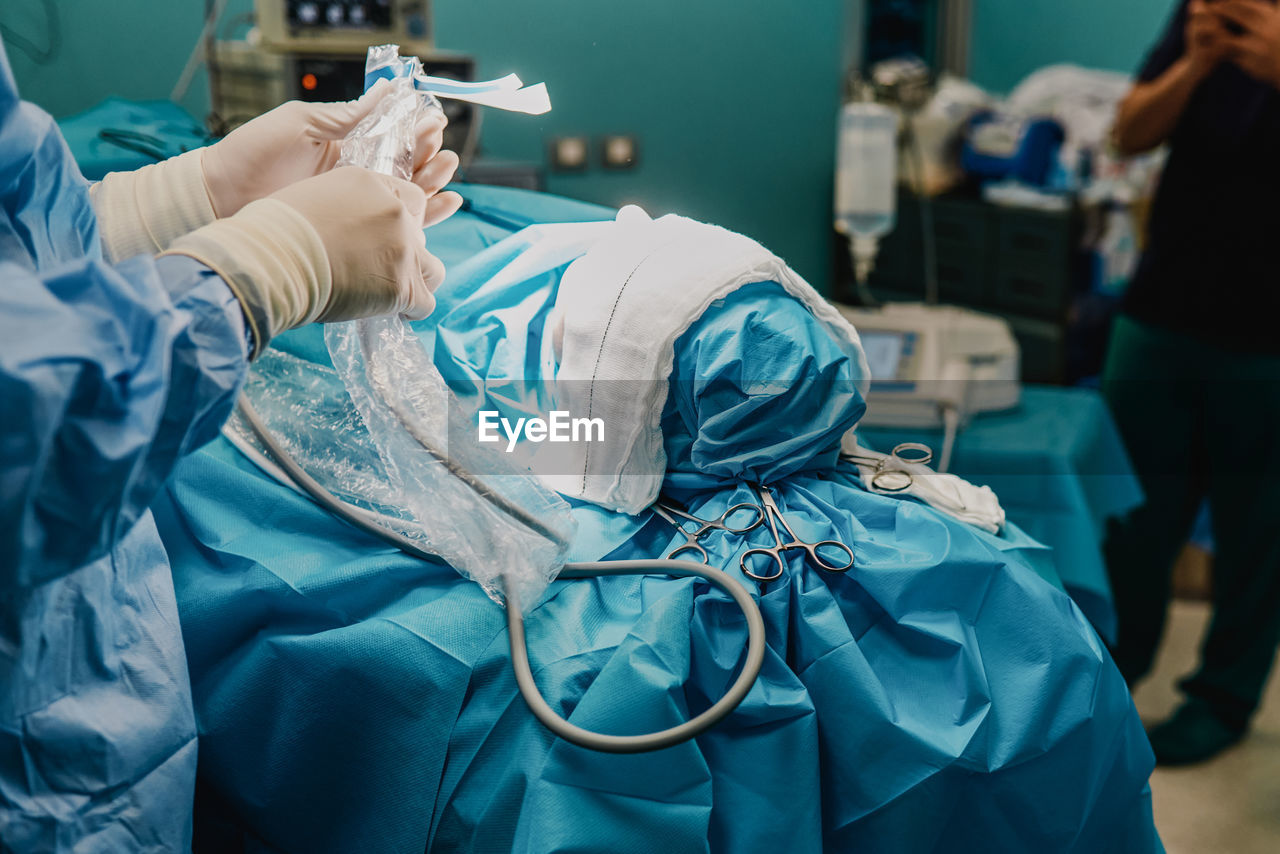 Surgeon team operating patient in surgical room at hospital - focus on scissors