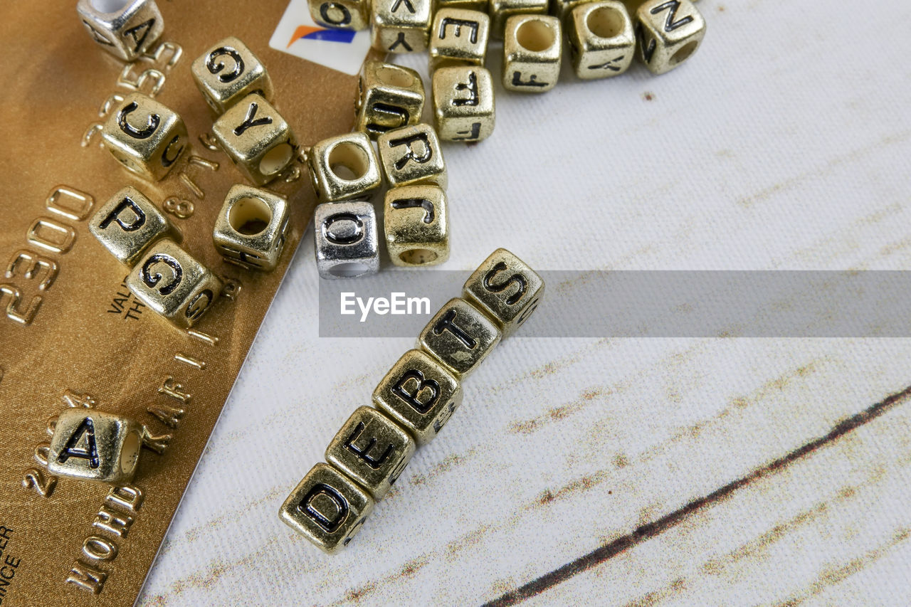 Close-up of debt text made with golden toy blocks on table