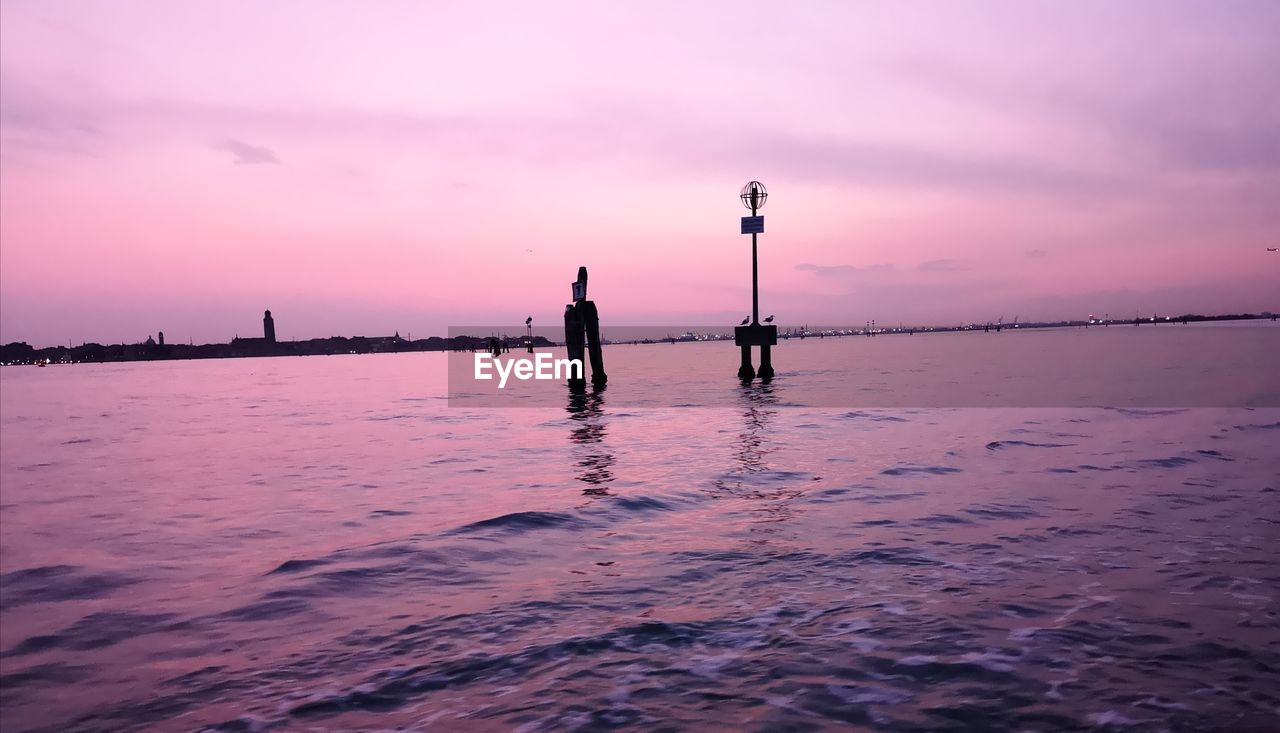 SILHOUETTE PEOPLE STANDING BY SEA AGAINST ORANGE SKY