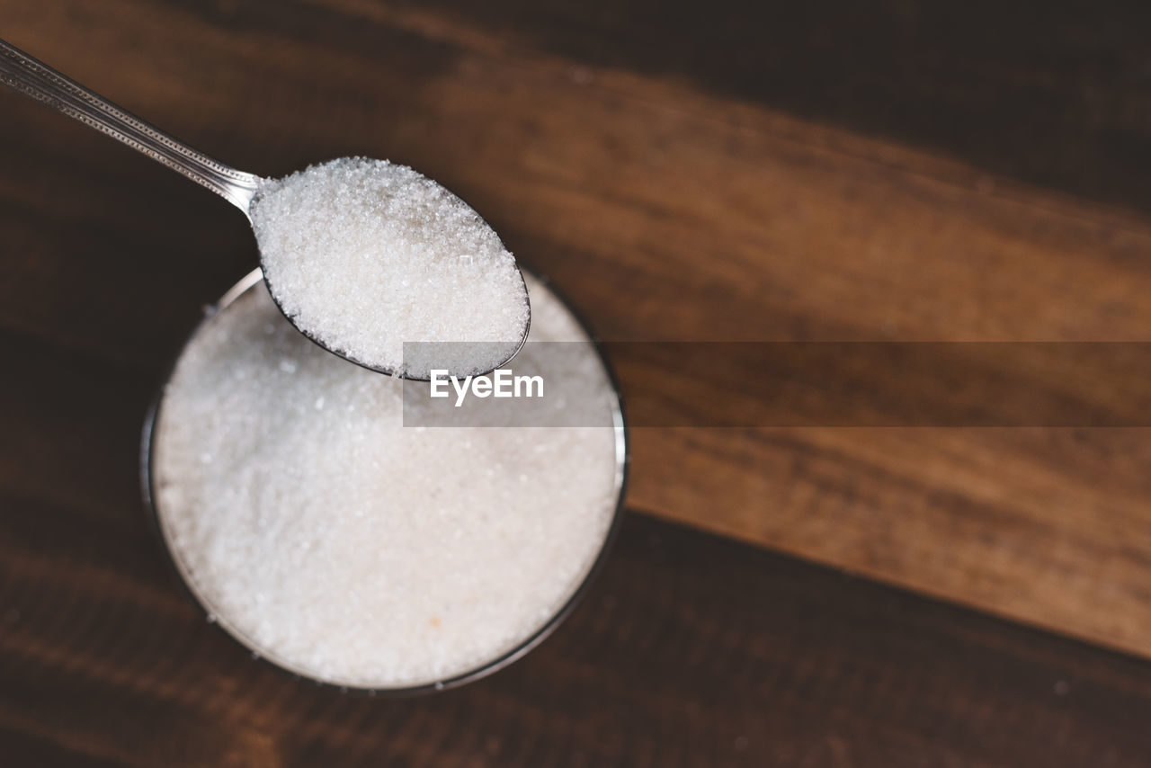 Sugar poured on a wooden table with diabetes word. concept of diabetes and unhealthy eating.