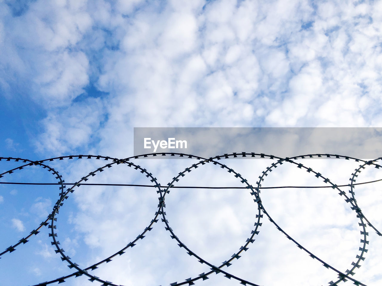 LOW ANGLE VIEW OF METAL FENCE AGAINST SKY