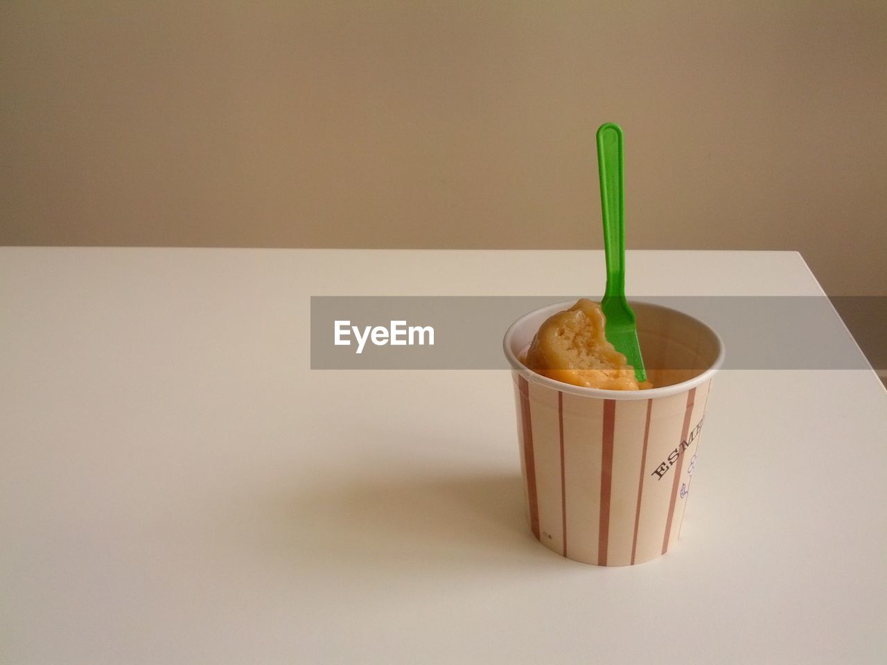Ice cream cup on table against wall