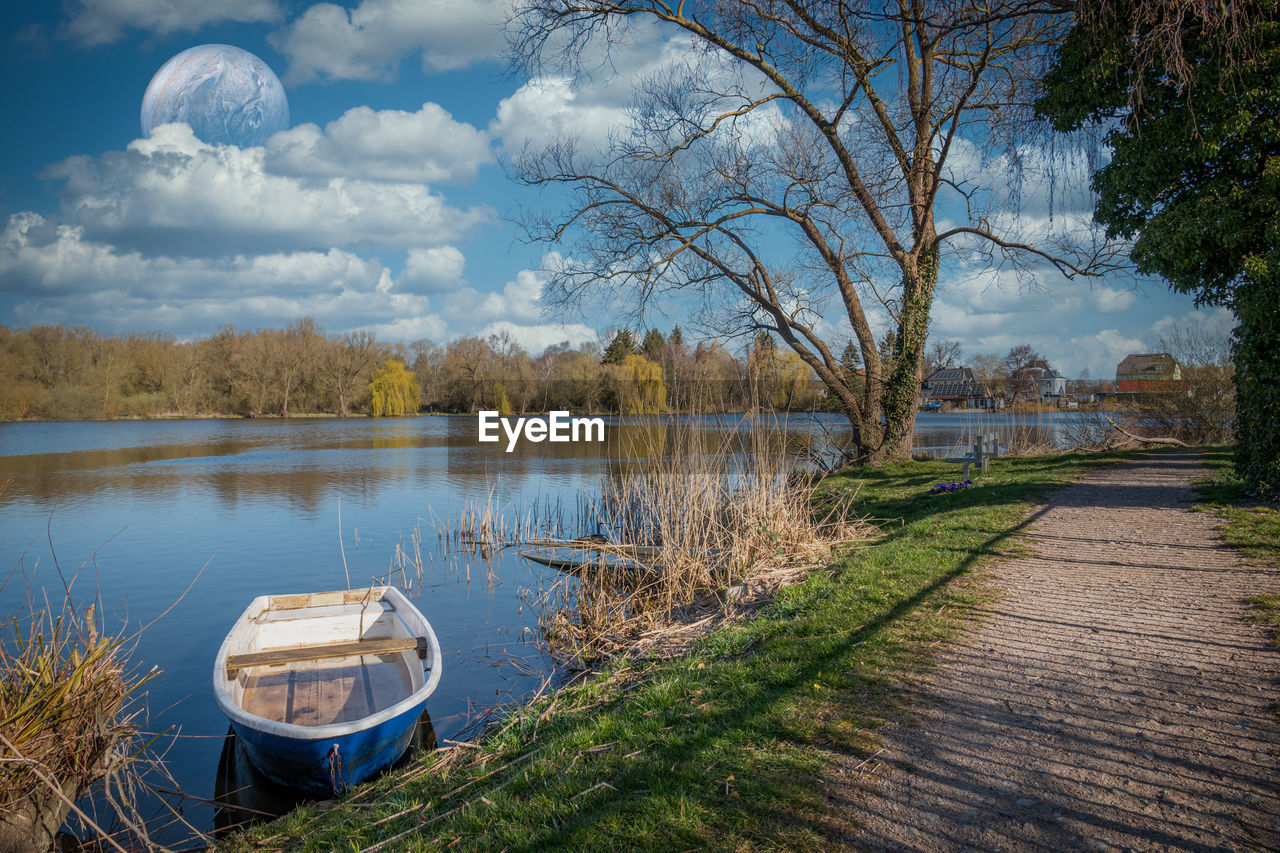 BOATS MOORED ON LAKE AGAINST SKY