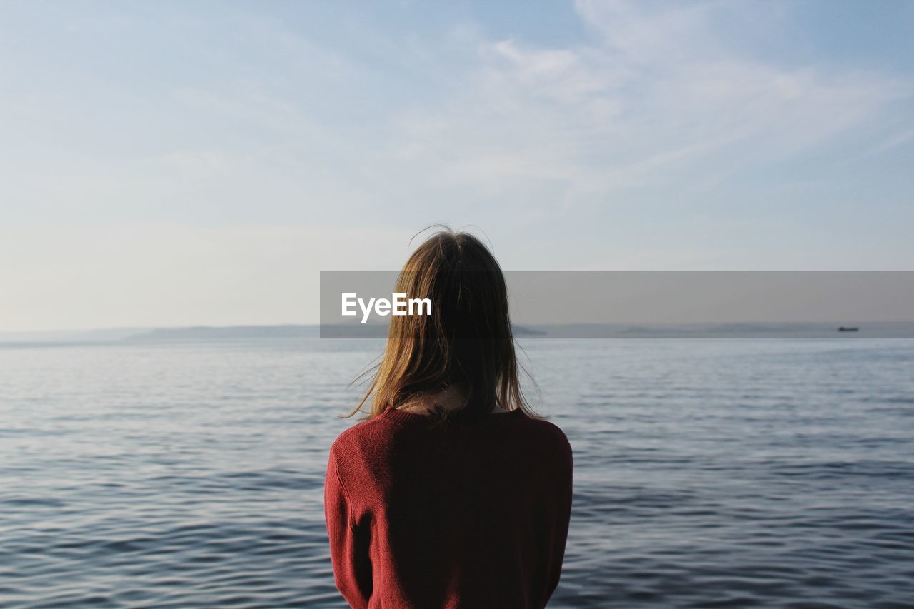 Rear view of woman standing against sea at beach