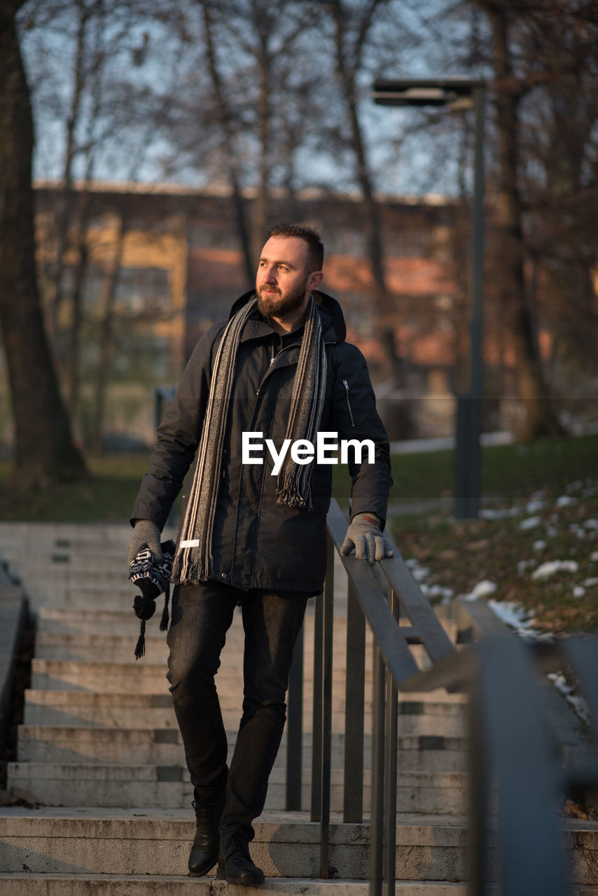 Young man in warm clothing moving down on steps at park