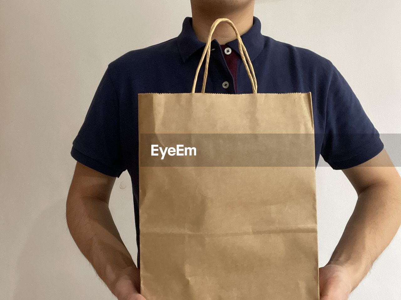 one person, clothing, t-shirt, sleeve, adult, studio shot, indoors, men, pocket, occupation, front view, business, standing, copy space, holding, shirt, young adult, bag, casual clothing, outerwear, collar, midsection