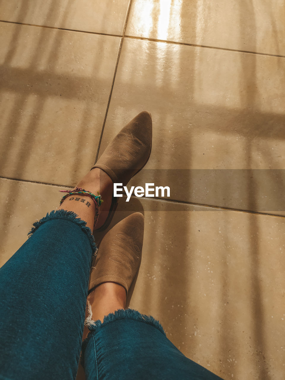 Low section of woman legs on tiled floor