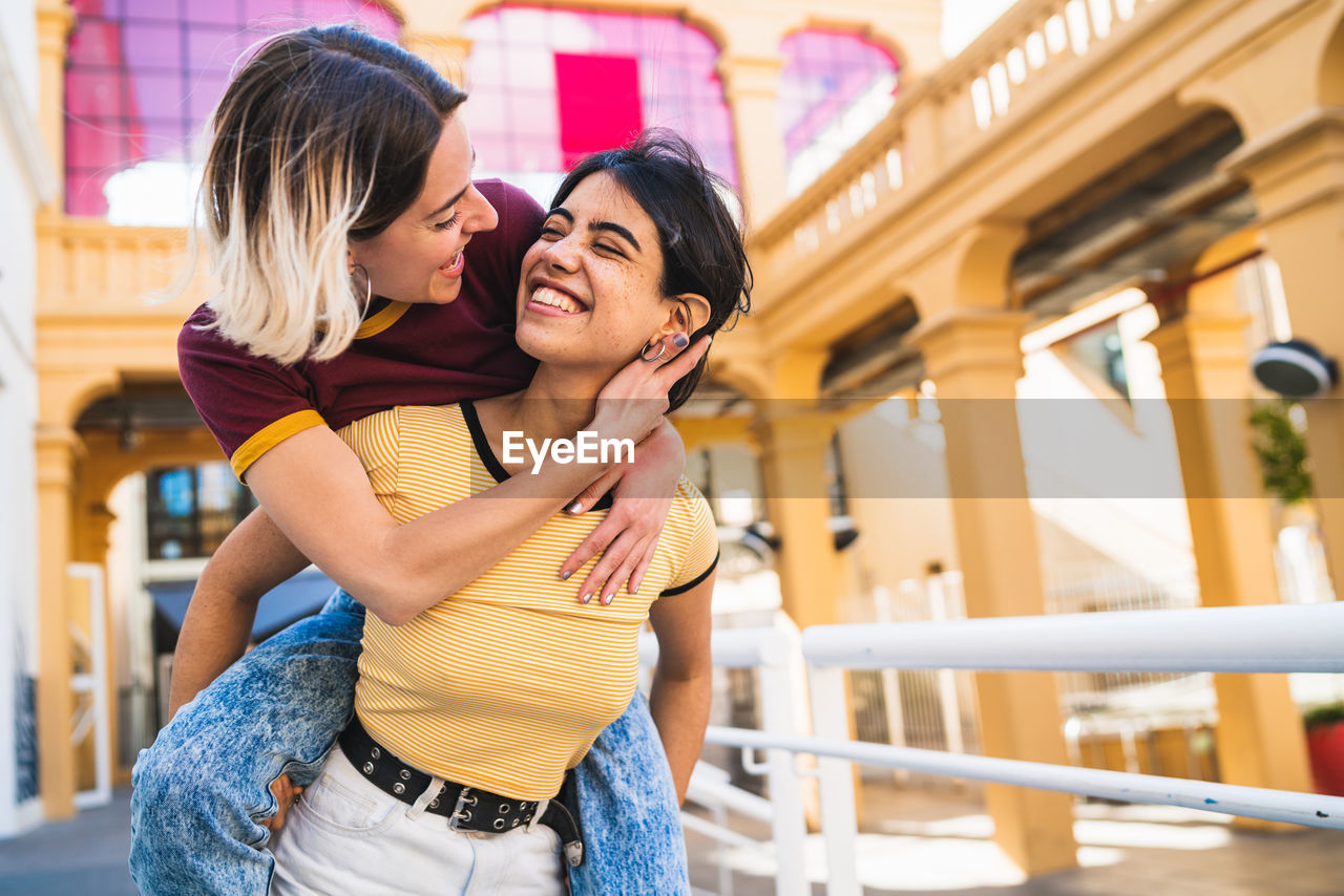 Laughing lesbian couple walking against building