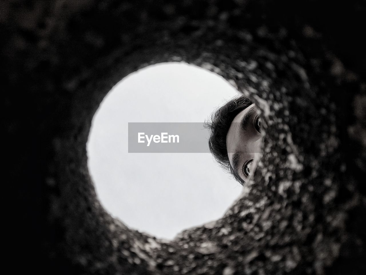 Cropped image of man against clear sky seen through hole