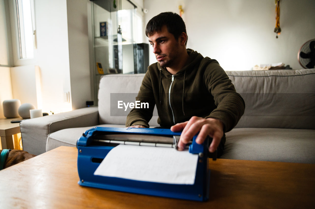 Visually impaired male typing on typewriter with tactile writing system at home