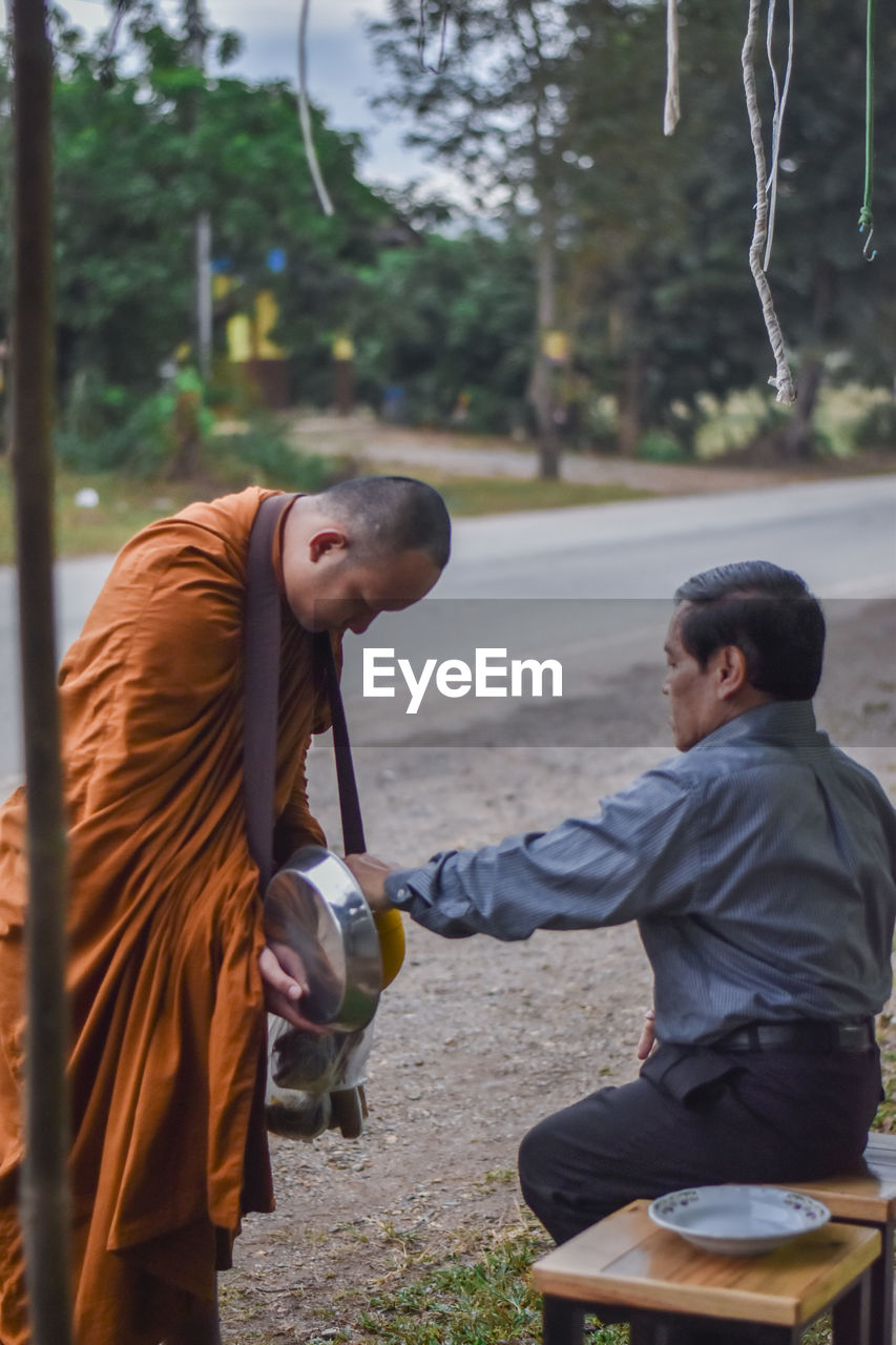 Man giving food to monk