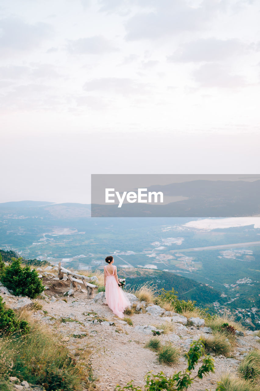 Rear view of woman sitting on landscape against sky