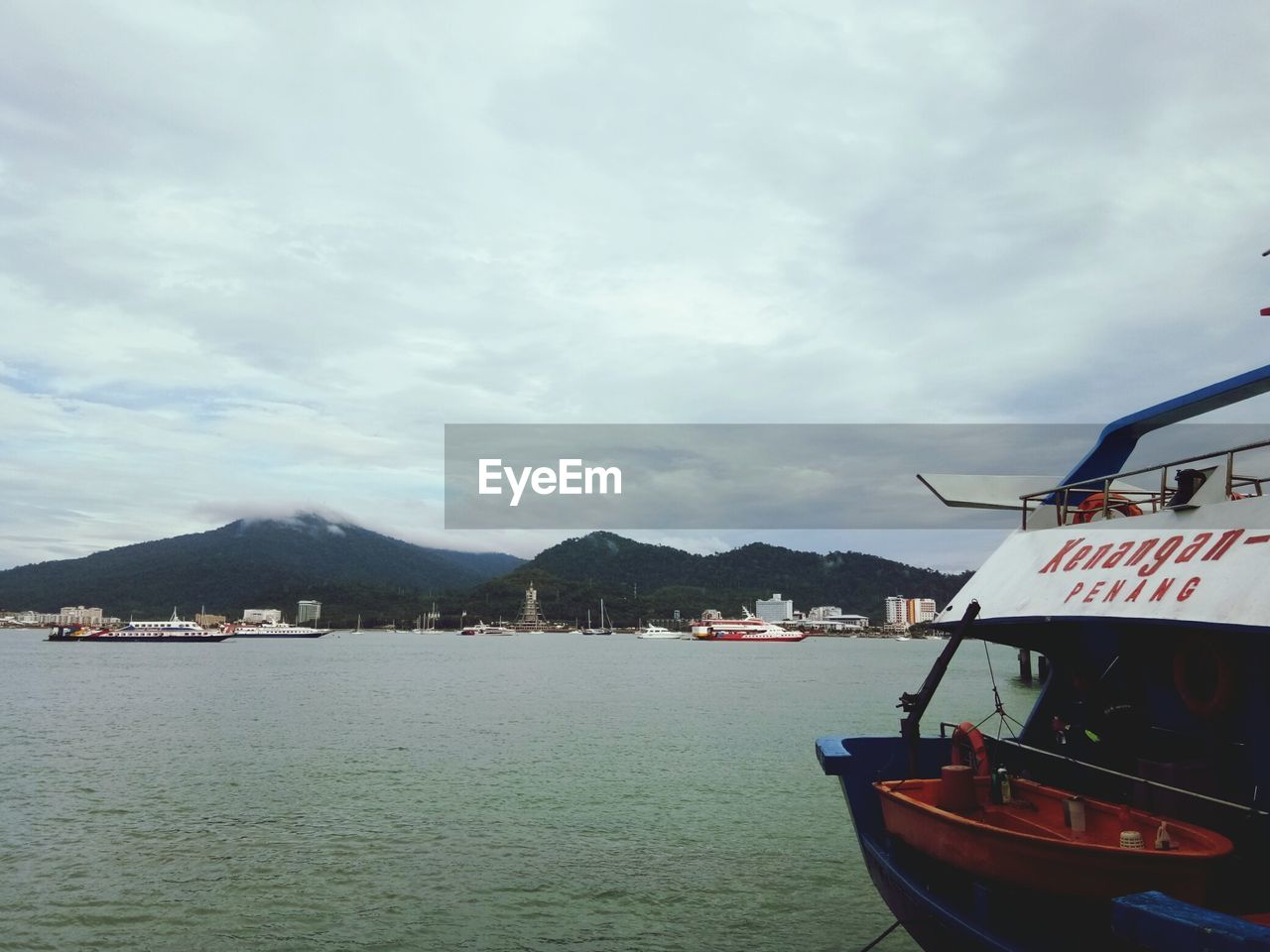 BOATS MOORED ON LAKE AGAINST SKY