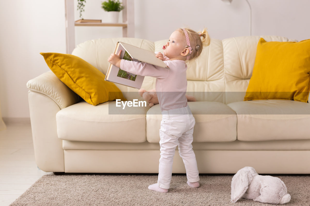 full length of young woman sitting on sofa at home