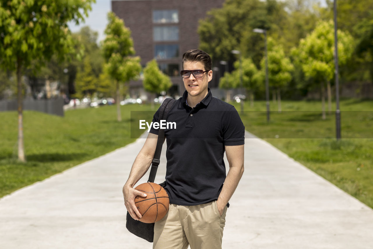 Close-up of mature man holding basketball while standing outdoors