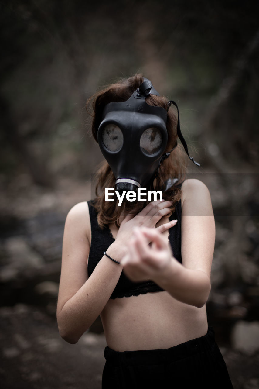 Portrait of woman wearing gas mask standing outdoors