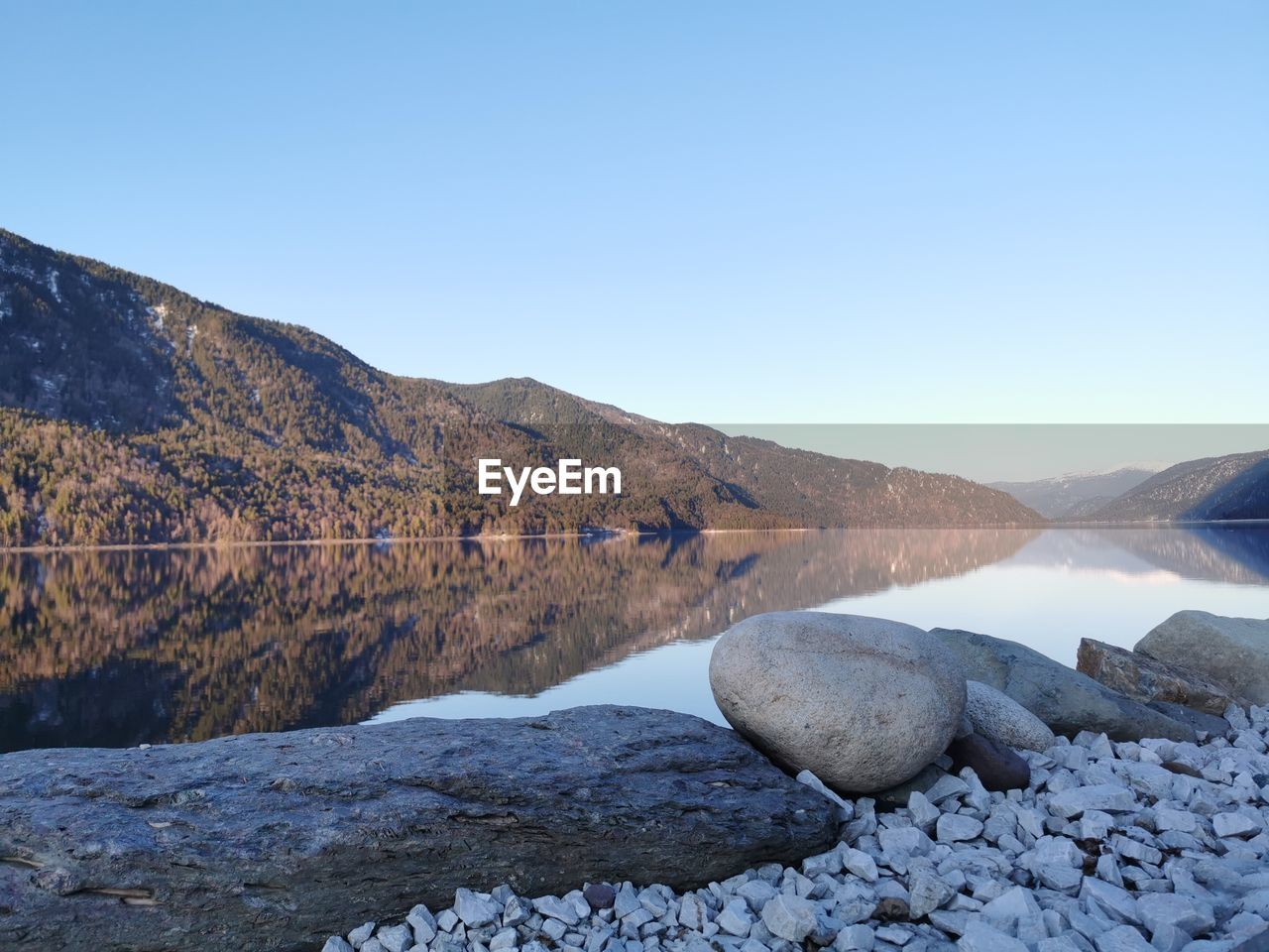 Scenic view of lake and mountains against clear blue sky