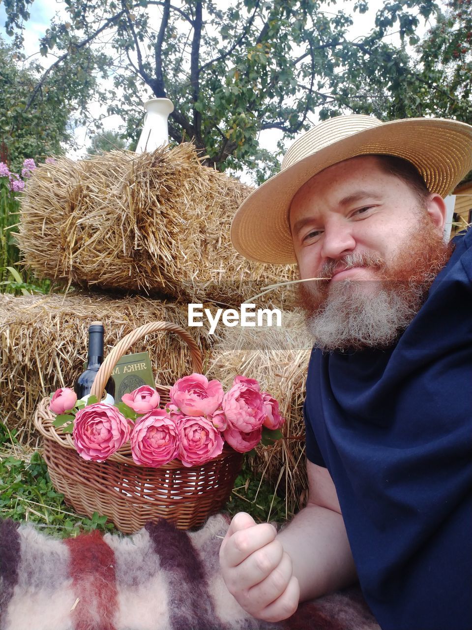 PORTRAIT OF MAN WITH PINK FLOWERS IN SUNLIGHT