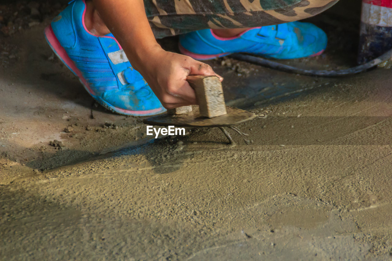 MIDSECTION OF MAN WORKING WITH SAND