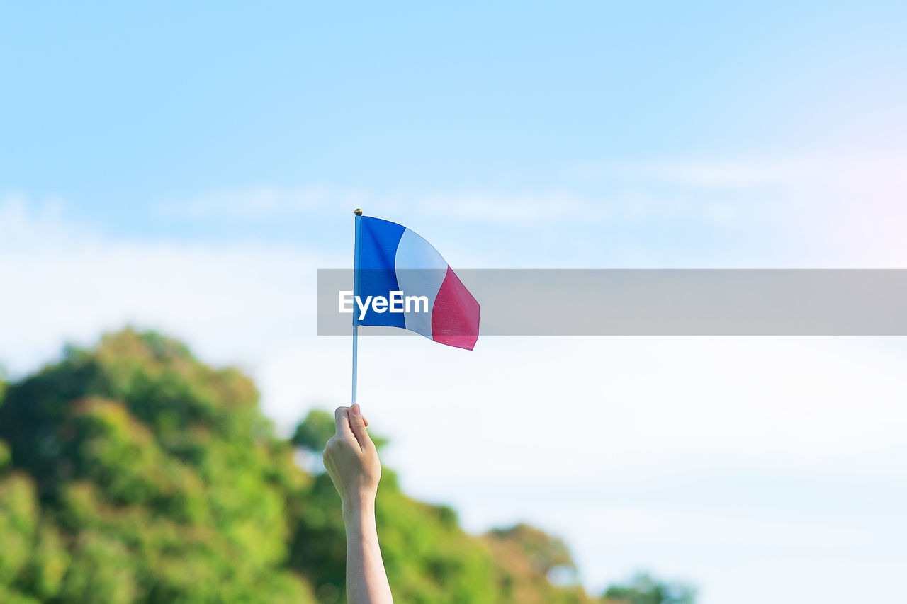 WOMAN HOLDING FLAG AGAINST SKY